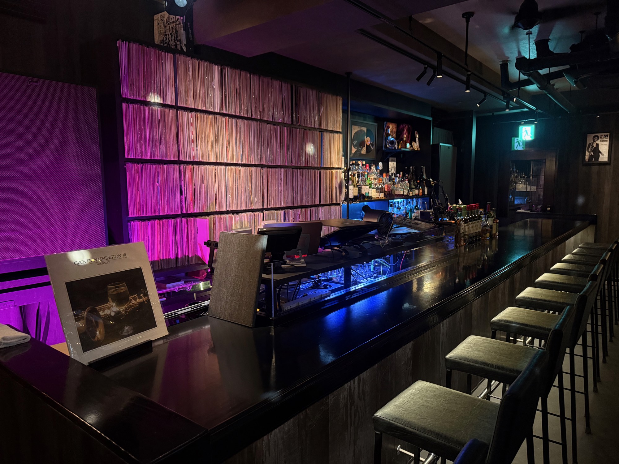 壁一面のレコード棚とカウンター。紫と青の照明が灯る BAR soul on の店内